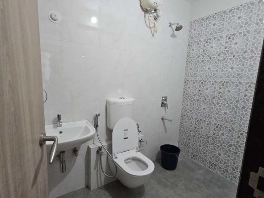 Modern bathroom with a shower area, western toilet, wash basin, mirror, and tiled walls